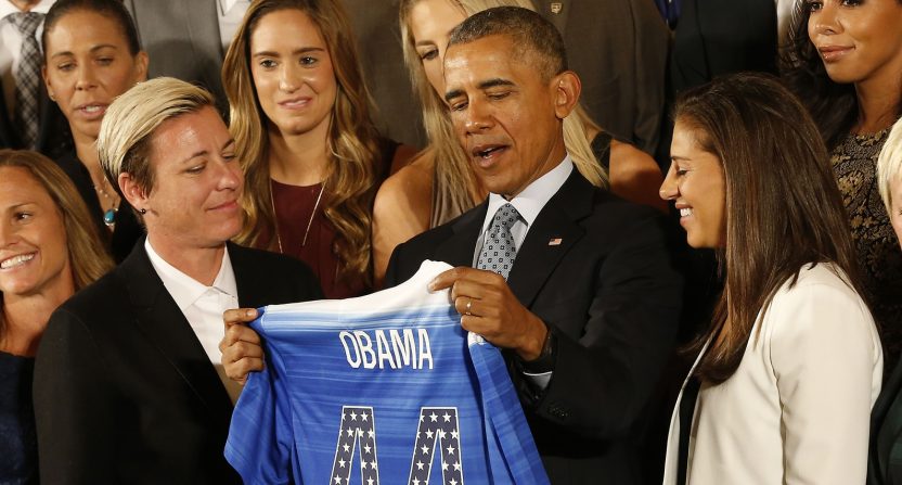 President Barack Obama (M) holds an honorary team jersey while talking with Team USA forward Abby Wambach (L) and midfielder Carli Lloyd (R) of the 2015 Women's World Cup champion U.S. Women's National Soccer Team at a ceremony honoring their world championship in the East Room at The White House.